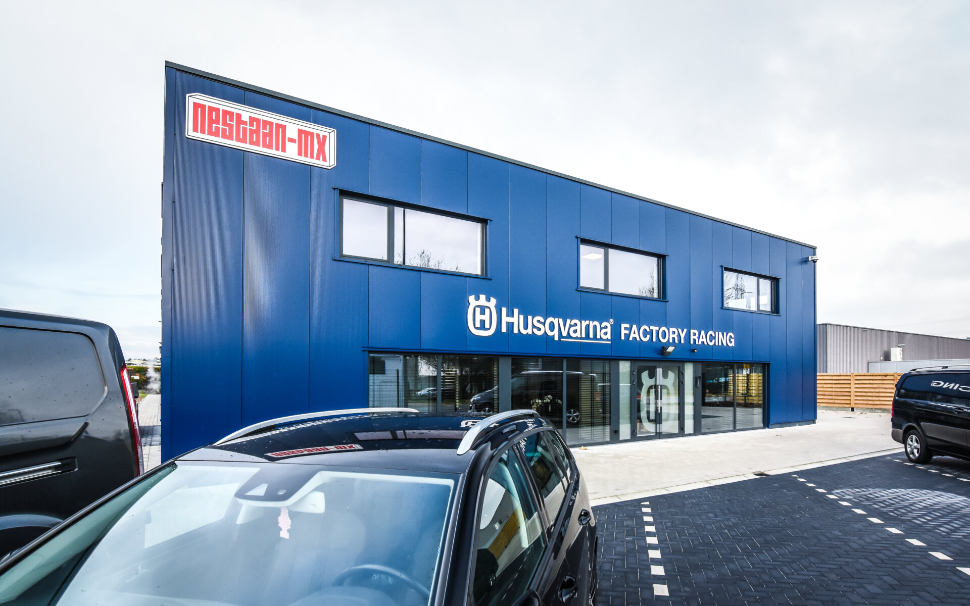 Bedrijfsgebouw van Husqvarna Racing in Lommel met blauwe gevel en grote raampartijen